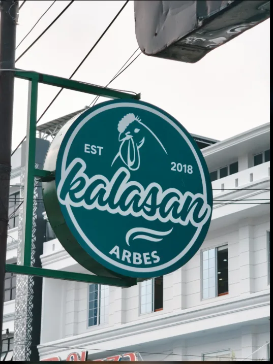 Papan nama asli Kalasan Arbes berwarna hijau dengan tulisan EST 2018 di depan restoran